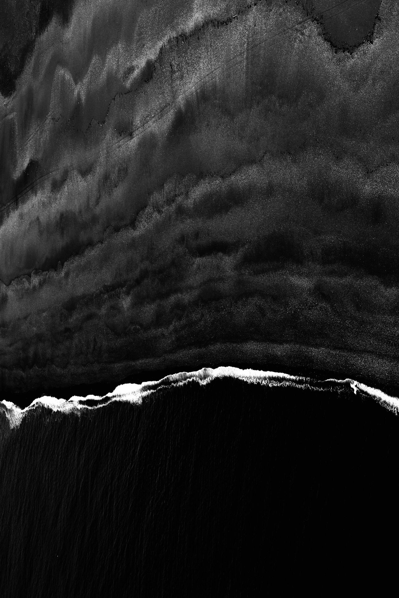 aerial black sand beach with wave
